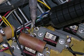 Removing excess solder to allow insertion of the new capacitor leads. The terminal below the solder pump has already been cleaned. Notice the fine transformer wires!