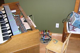 A shelf clamped to the organ provides extra work space. The oscilloscope is for measuring tone generator output.