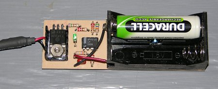 The completed charger with one cell in place. The 2-cell holder was made by cutting the outer positions off of a 4-cell holder. Notice how the thermistor is installed so as to make physical contact with the cells being charged. A small heatsink keeps Q1 cool. The completed charger with one cell in place. The 2-cell holder was made by cutting the outer positions off of a 4-cell holder. Notice how the thermistor is installed so as to make physical contact with the cells being charged. A small heatsink keeps Q1 cool.