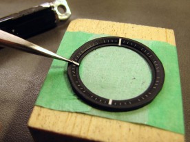 Applying the self-adhesive hour indices with watchmaker's tweezers.