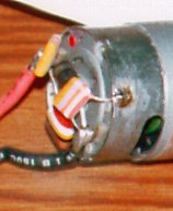 Photo 1. A typical three-capacitor filter installation on a ferrite motor. These particular capacitors are older style high-voltage ones; newer ones would be smaller. The black cylinder is the ESCs freewheeling diode.